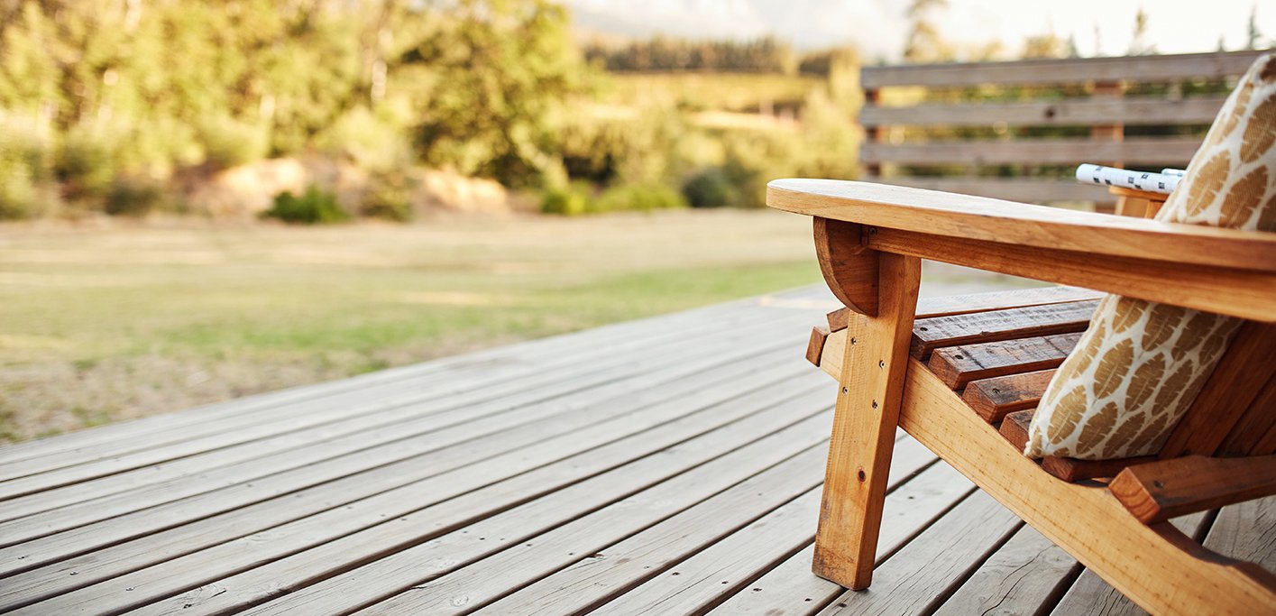 Aussicht von einer Holzterrasse mit Holzstuhl zum Garten