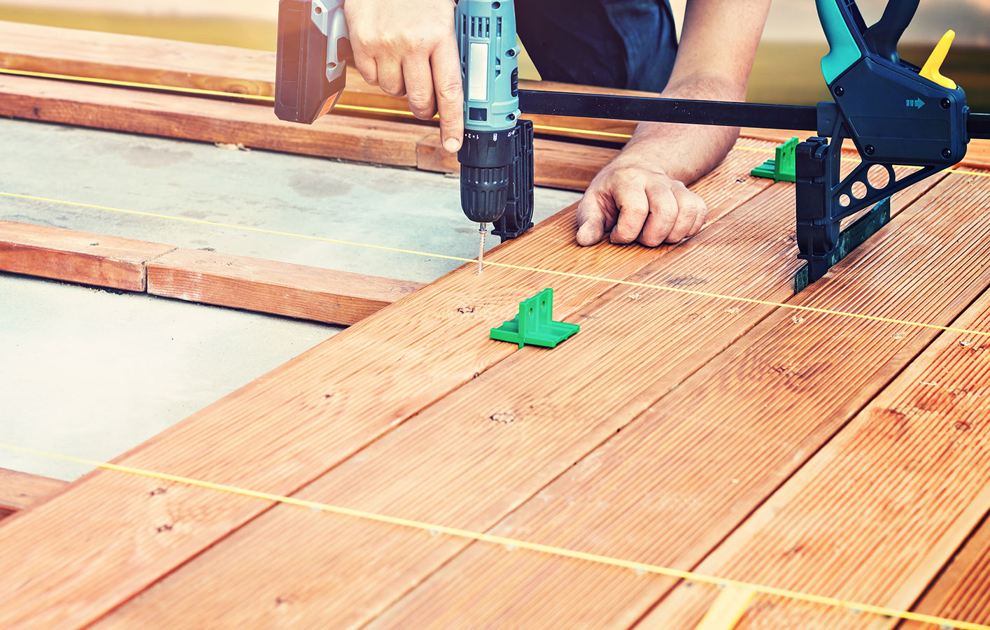 Handwerker verlegt Terrassendielen aus Holz